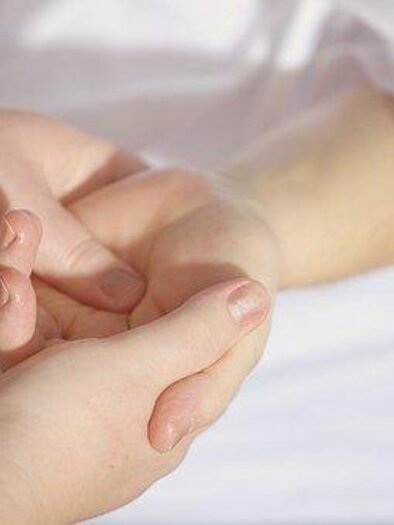 Hände, die sich sanft berühren, drücken Zuneigung und Unterstützung aus. Der Hintergrund ist hell und neutral, was eine ruhige Atmosphäre schafft. | © Symbolfoto