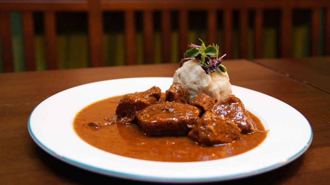 <p>Ein köstliches Gericht mit zartem Fleisch in einer reichhaltigen Sauce, serviert mit einem Knödel. Die Präsentation ist ansprechend und garnierte mit frischen Kräutern.</p> | © Glöckl Bräu