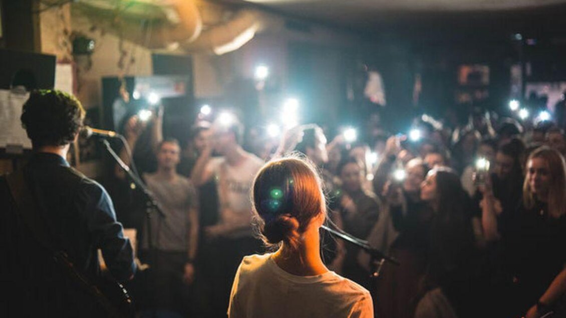Eine Sängerin steht auf der Bühne und tritt vor einem begeisterten Publikum auf. Die Zuschauer halten ihre Telefone in die Höhe und filmen das Konzert. | © Glam Feldbach