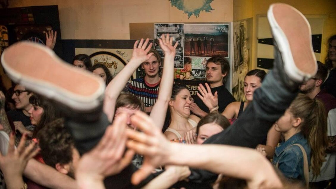 Eine lebhafte Partyszene mit fröhlichen Leuten, die tanzen und Spaß haben. Hände und Füße sind in der Luft, während die Menge feiert. | © Glam Feldbach