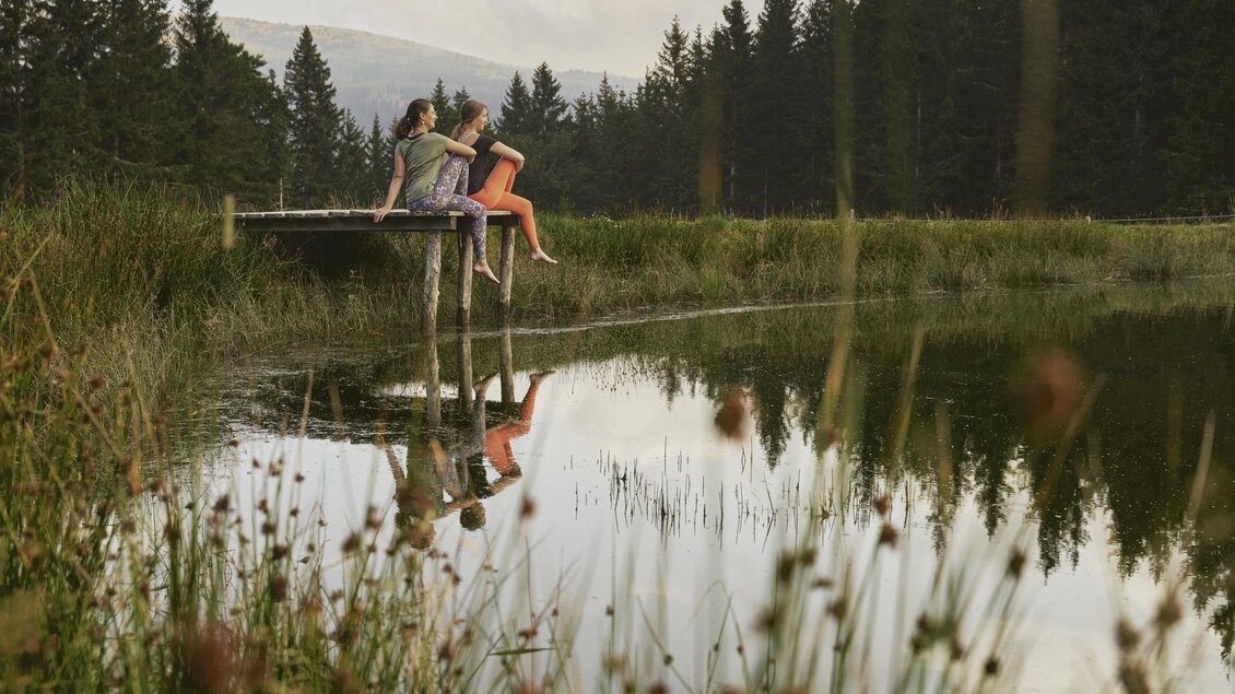 Man sieht eine Familie auf einem Steg sitzen.  | © Oststeiermark Tourismus
