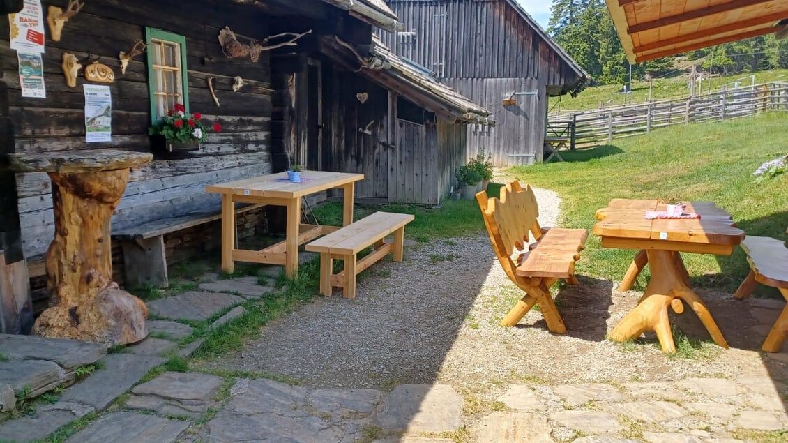 Eine gemütliche Terrasse mit Holzmöbeln und Blick auf eine Wiese. Im Hintergrund steht ein traditionelles Holzhaus. | © Fam. Lipp