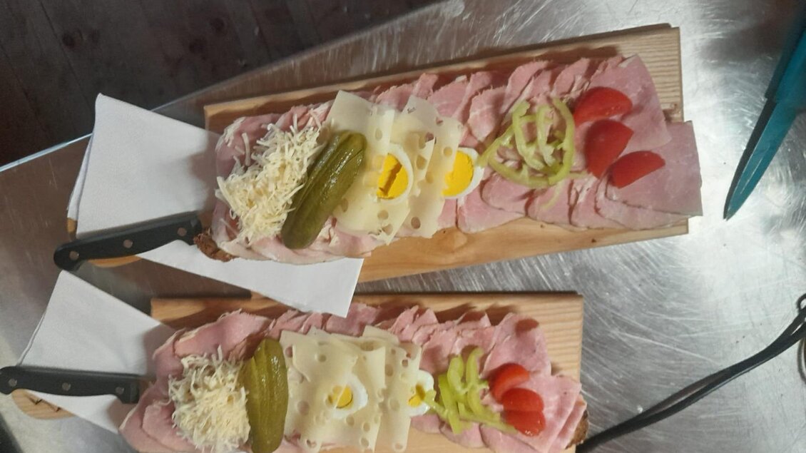 Zwei Holzplatten mit Aufschnitt, Käse und frischem Gemüse. Darauf liegen Gürkchen, Tomaten und Eier als garnierte Snacks. | © Fam. Lipp