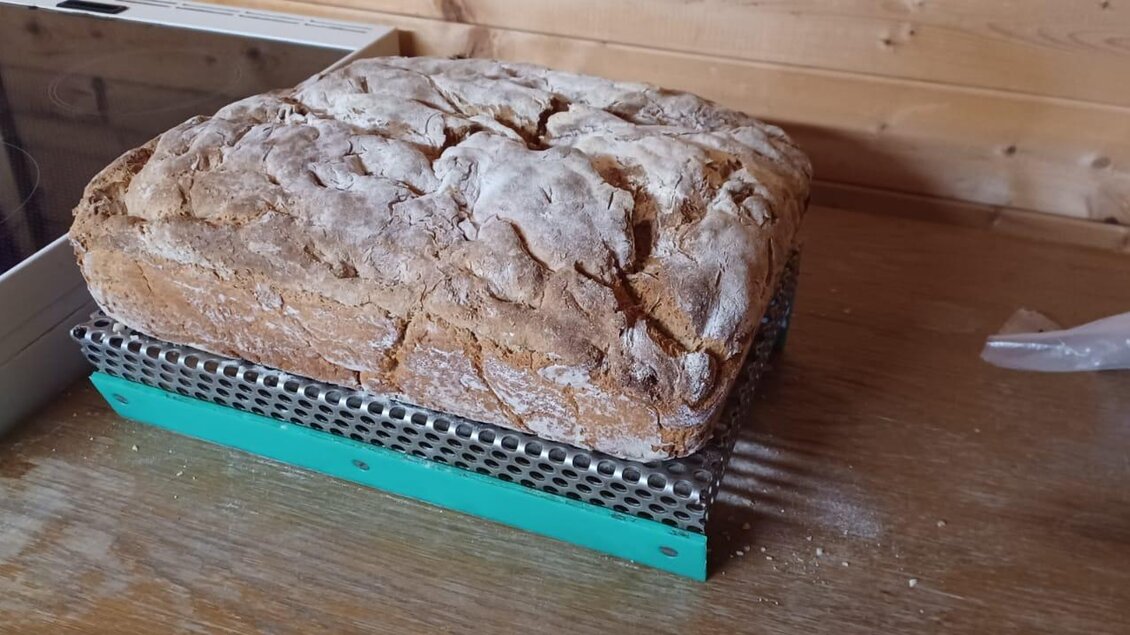 Ein frisch gebackenes Brot liegt auf einem Gitter. Der Holzuntergrund sorgt für einen rustikalen Look. | © Fam. Lipp