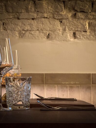 Table setting with wine glasses and a crystal glass, in front of a bright, brick wall. | © Glockenspielkeller