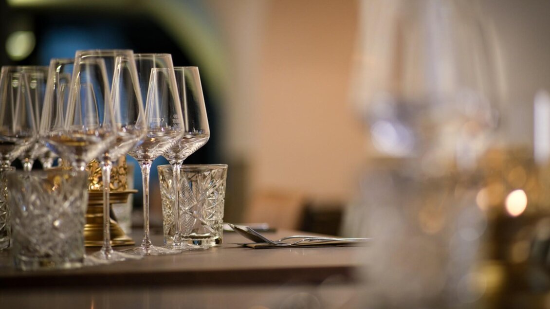 Elegante Tischdekoration mit Kristallgläsern und Weingläsern, die in sanftem Licht glänzen. | © Glockenspielkeller