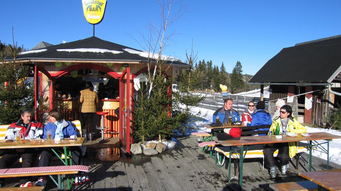 Eine gemütliche Skihütte mit Sitzgelegenheiten im Schnee. Die Gäste genießen die Sonne an klaren, blauen Himmel. | © Schlosshotel Seewirt