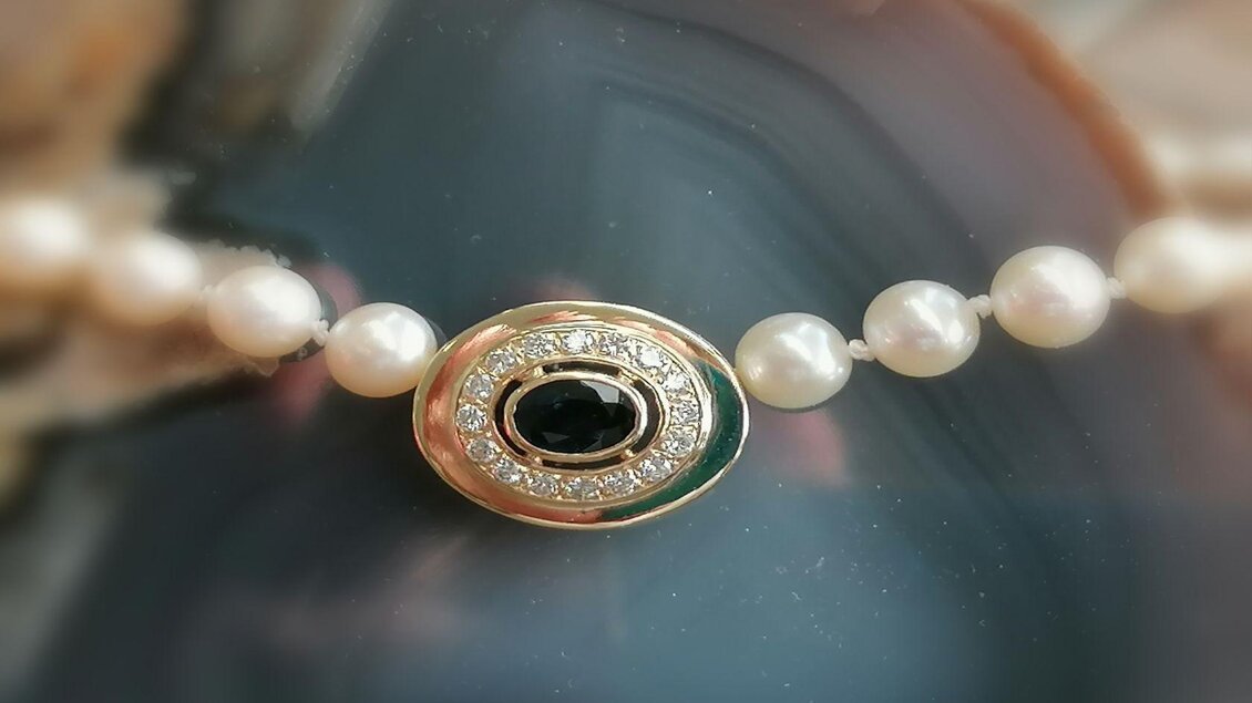 Eine elegante Halskette aus Perlen mit einem Glanzstein im Mittelpunkt. Der Stein ist von funkelnden Diamanten umgeben und verleiht der Kette einen luxuriösen Look. | © Anita Seebacher