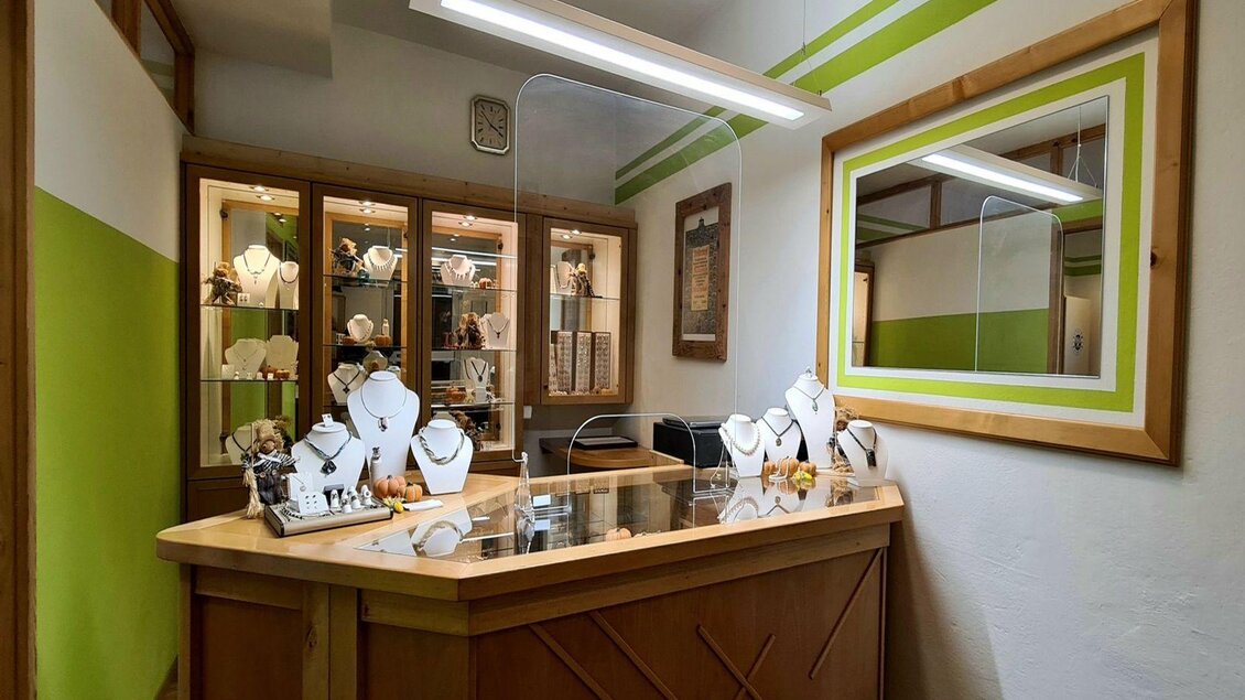 Ein elegantes Schmuckgeschäft mit einer Holztheke und Vitrinen voller Schmuckstücke. Die Wände sind in einem modernen Design mit grünen Akzenten gehalten. | © Stephanie Bor