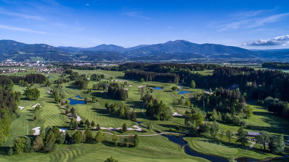 Eine weite Golfanlage mit gepflegten Fairways und vielen Bäumen. Im Hintergrund sind sanfte Hügel und ein klarer, blauer Himmel zu sehen. | © Golf Club Murtal