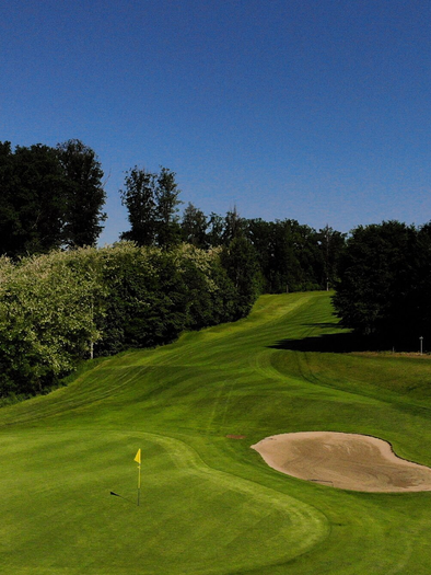 Eine Golfanlage mit grünem Rasen und einem Sandbunker. Im Hintergrund sind Bäume und ein blauer Himmel zu sehen. | © GEPA-pictures - Murhof Gruppe