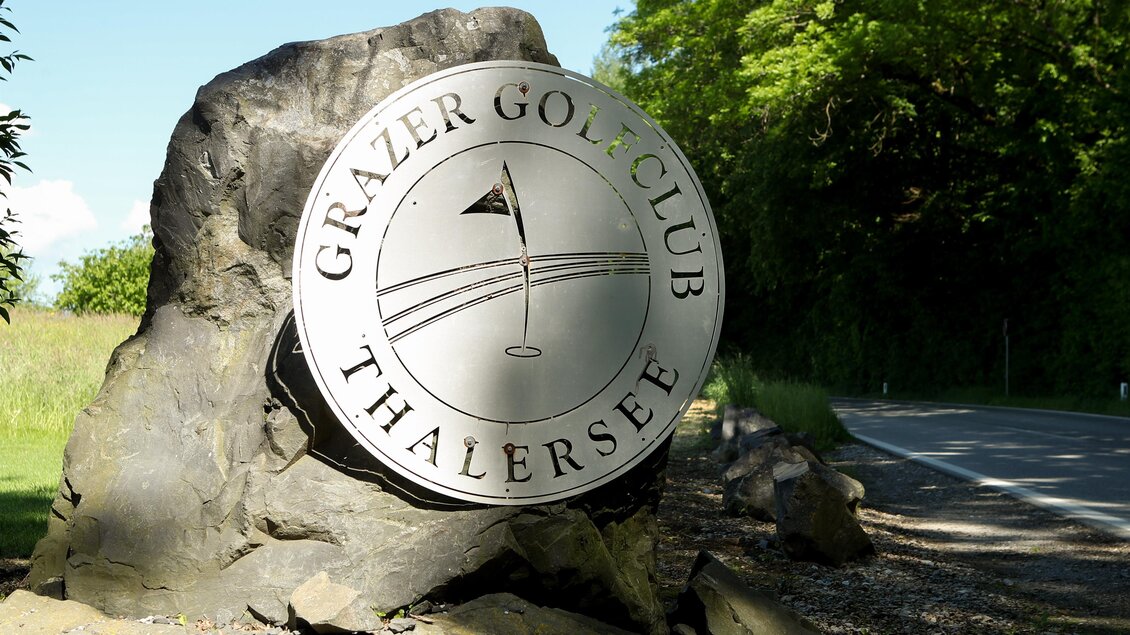 Ein Schild aus Metall mit dem Logo des Grazer Golfclubs Thalersee. Es steht auf einem großen Stein an der Straßenseite. | © GEPA Pictures