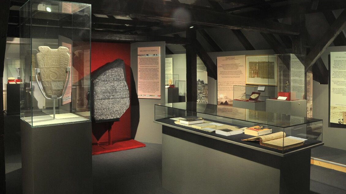 Eine Ausstellung mit historischen Artefakten in einem Museum. Im Vordergrund sind Vitrinen mit verschiedenen Objekten und Informationsschildern zu sehen. | © Gröbming Museum