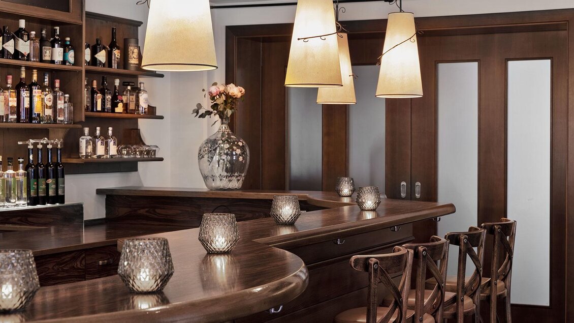 Eine stilvolle Bar mit Holzmöbeln und sanfter Beleuchtung. Die Regale sind mit verschiedenen Spirituosen und Gläsern gefüllt. | © GrafenWirt