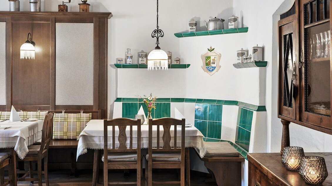 Ein gemütliches Restaurant mit Holzmöbeln und einer einladenden Ecke. Die grün geflieste Wand und die Tischdekoration schaffen eine angenehme Atmosphäre. | © GrafenWirt