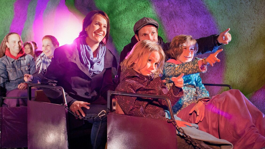 Kinder und Erwachsene fahren mit der bunten Grazer Märchenbahn im Schlossberg | © una-Grafik Krausz