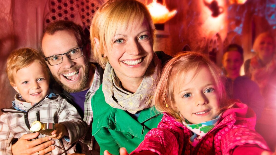 Familie mit Kindern fährt durch orientalische Kulisse der Grazer Märchenbahn  | © una-Grafik Krausz