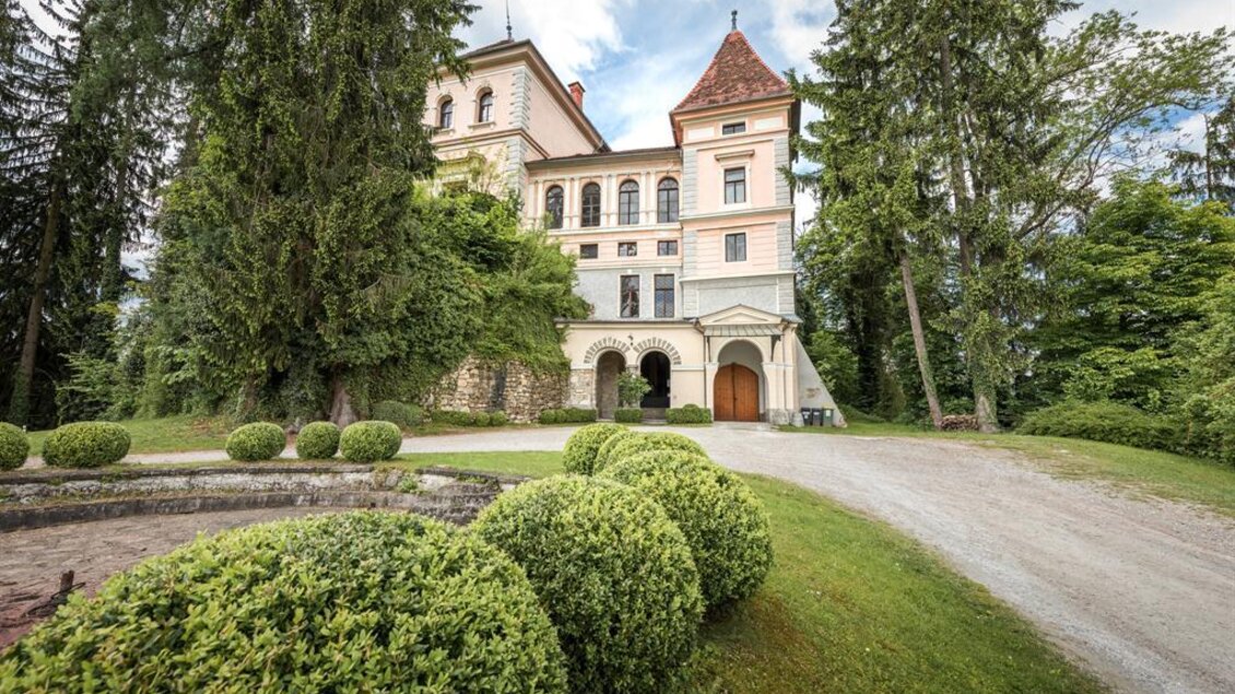 Ein historisches Schloss umgeben von grünen Bäumen und Sträuchern. Der Eingang ist mit schönem Rasen und Hecken gestaltet. | © Dieter Sajovic