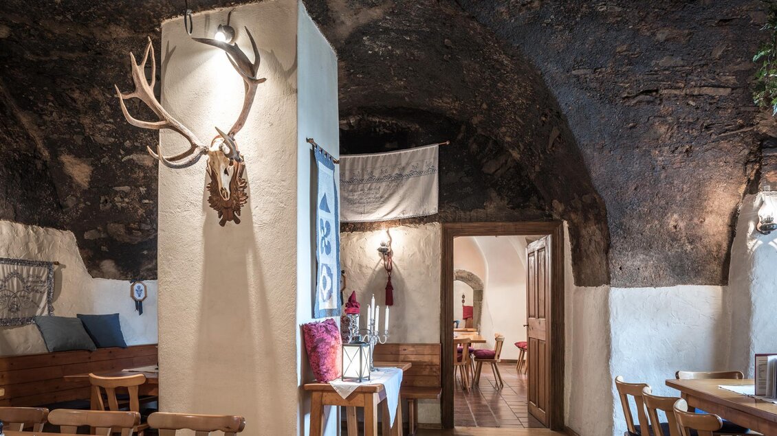Ein gemütliches Restaurant in einem historischen Keller mit Holzmöbeln. An der Wand hängen dekorative Geweihe und es gibt eine warme, einladende Atmosphäre. | © Die Abbilderei