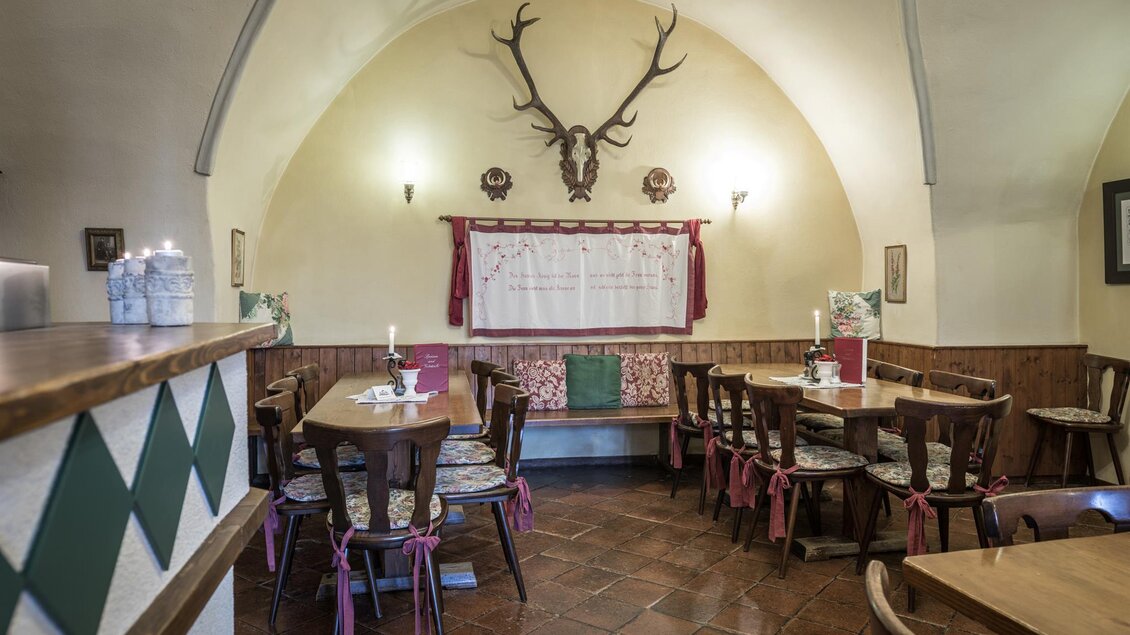 Ein gemütliches Restaurant mit Holztischen und Bänken. An der Wand hängen Hirschgeweih und traditionelle Dekorationen. | © Die Abbilderei