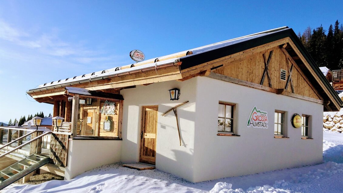 Ein charmantes Gebäude in den Bergen, umgeben von Schnee. Die Holzelemente und die schöne Architektur verleihen ihm einen gemütlichen Charakter.