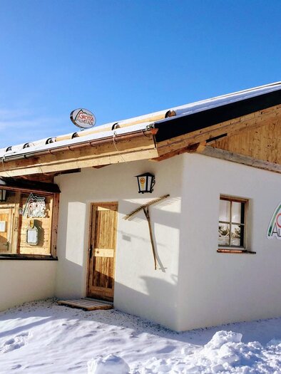 A charming building in the mountains, surrounded by snow. The wooden elements and the beautiful architecture give it a cozy character.