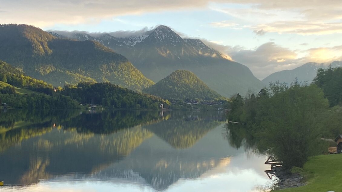 Eine ruhige Landschaft mit Bergen und einem klaren See. Die Berge spiegeln sich im Wasser und der Himmel ist bewölkt. | © Bettina Scheck