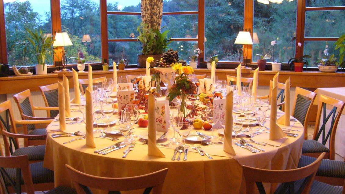 Rund gedeckter Tisch mit Herbstdeko, Stoffservietten und Fensterblick. | © Häuserl im Wald - Legenstein