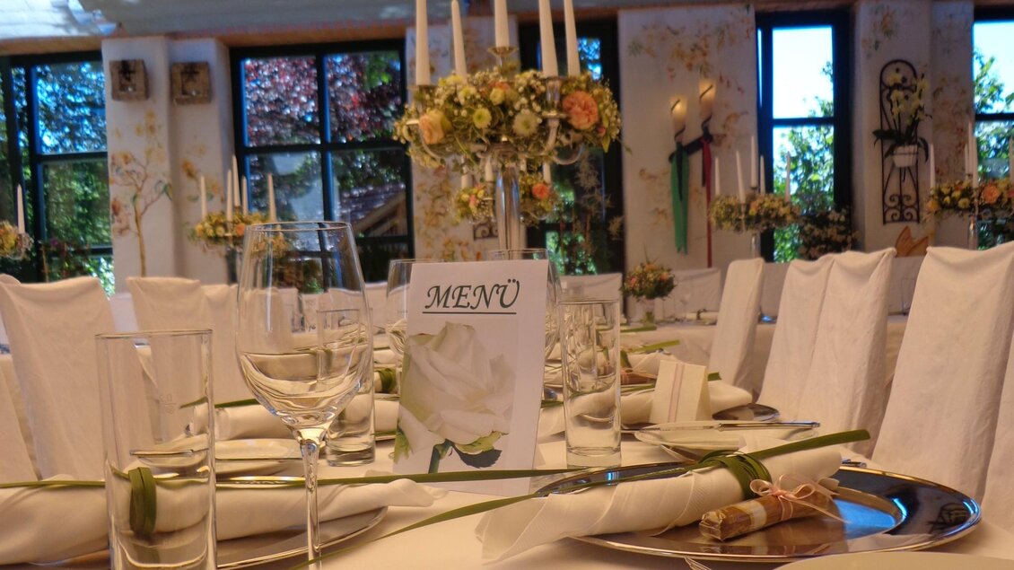 Nahaufnahme gedeckter Hochzeitstisch mit Menükarte, Kerzen und Blumenschmuck. | © Häuserl im Wald - Legenstein