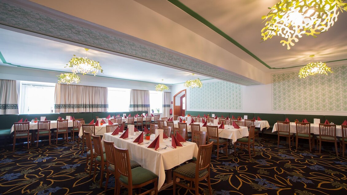 Ein eleganter Speisesaal mit Tischen, die schön eingedeckt sind. Die Wände sind hell gestaltet, und die Deckenleuchten verleihen dem Raum eine angenehme Atmosphäre. | © www.weisser-hirsch.at