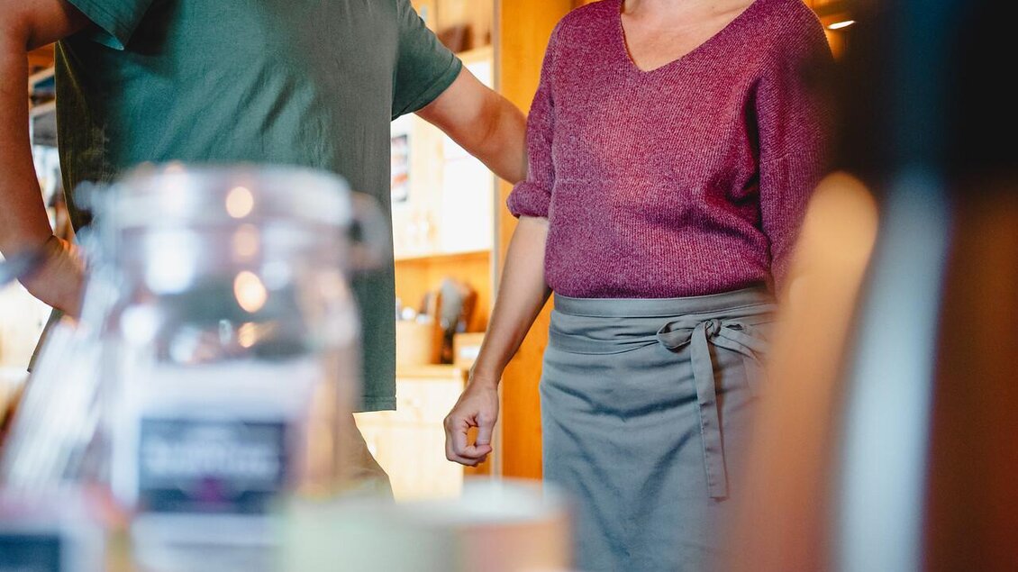Ein freundliches Gespräch zwischen zwei Personen in einem gemütlichen Raum. Im Vordergrund sind verschiedene Tassen und Kaffeekannen sichtbar. | © Christoph Lukas
