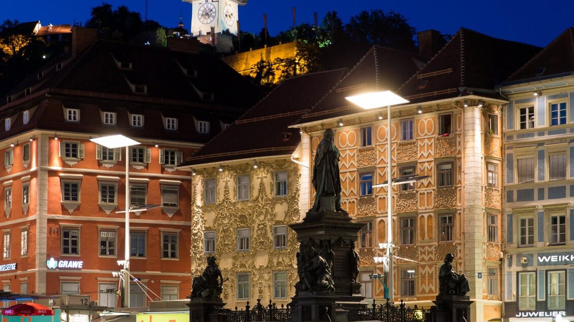 Nachtaufnahme vom Grazer Hauptplatz mit beleuchtetem Uhrturm und Brunnen | © Graz Tourismus-Harry Schiffer