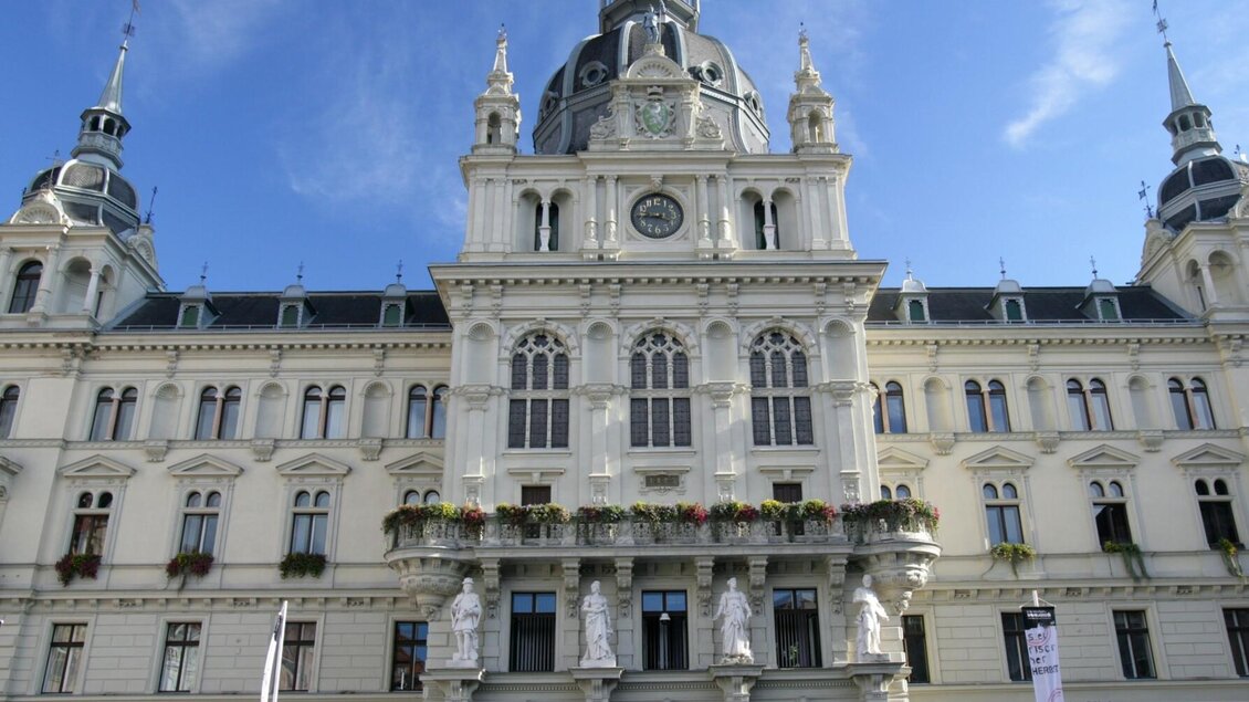 Frontalansicht des Grazer Rathauses mit Türmen, Figuren im barocken Baustil und Blumenschmuck | © Graz Tourismus-Harry Schiffer