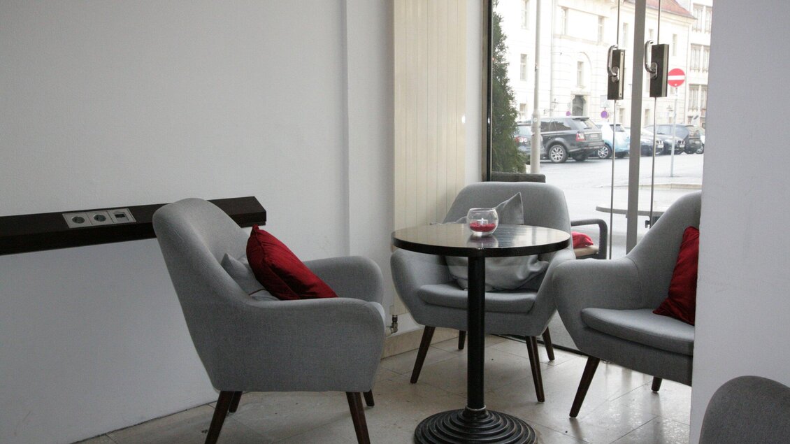 Ein gemütlicher Innenraum mit grauen Sesseln und einem kleinen Tisch. Große Fenster sorgen für viel natürliches Licht. | © Haus 4