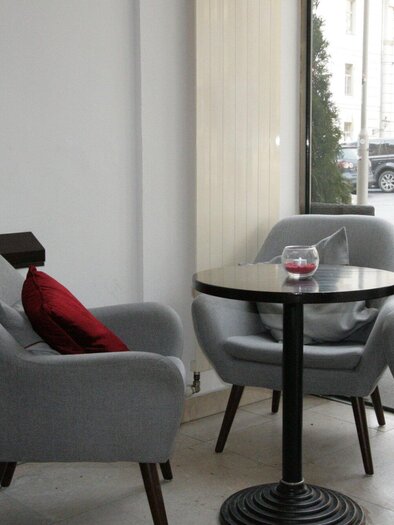 A cozy interior with gray armchairs and a small table. Large windows provide plenty of natural light. | © Haus 4