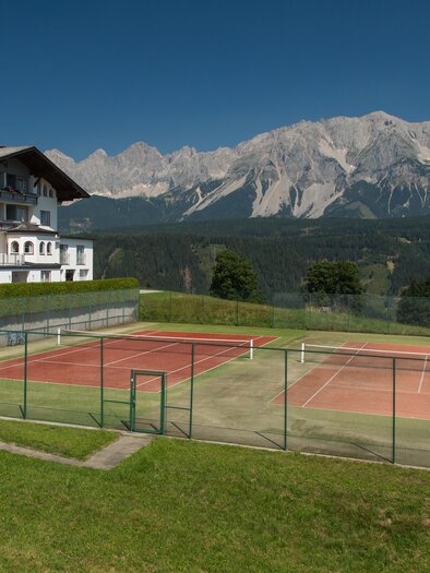 Ein malerisches Chalet mit Blick auf die Berge und zwei Tennisplätze. Die Umgebung ist grün und einladend. | © Haus Central