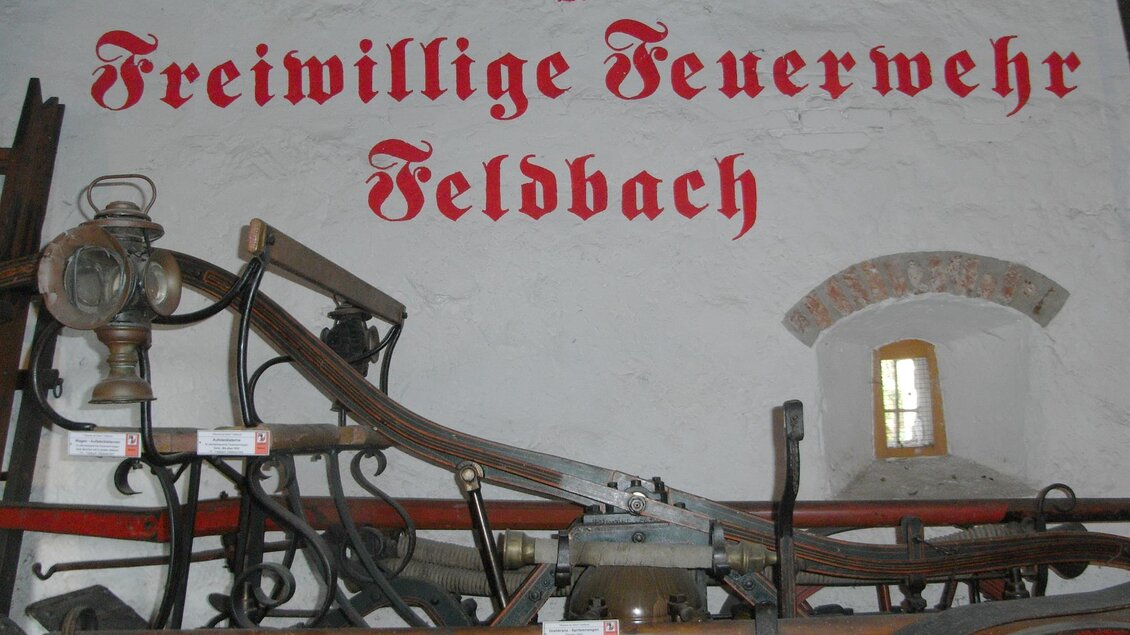 Ein historisches Feuerwehrfahrzeug mit einer alten Lampe. Im Hintergrund steht der Schriftzug „Freiwillige Feuerwehr Feldbach“. | © Stadtgemeinde Feldbach