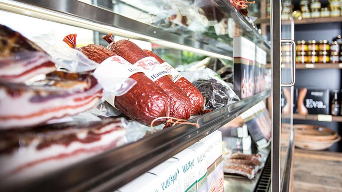 Eine Auslage mit verschiedenen Wurstwaren und Schinken. Die Produkte sind sorgfältig angerichtet und gut sichtbar. | © Heimatgold