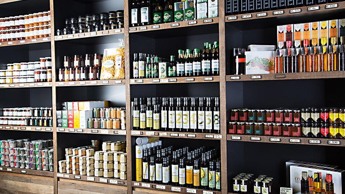 Ein gut sortierter Verkaufsregal mit verschiedenen Gläsern, Ölen und Saucen. Die Regale sind aus Holz und die Produkte sind farbenfroh angeordnet. | © Heimatgold
