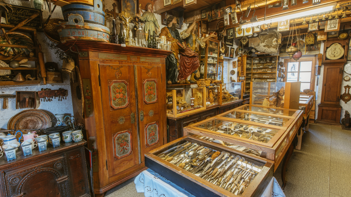 Ein einladendes Antiquitätengeschäft mit zahlreichen alten Möbeln und Sammlerstücken. Vitrinen voller antiquarischer Gegenstände und dekorativer Elemente zieren den Raum. | © Stephan Pelizzari