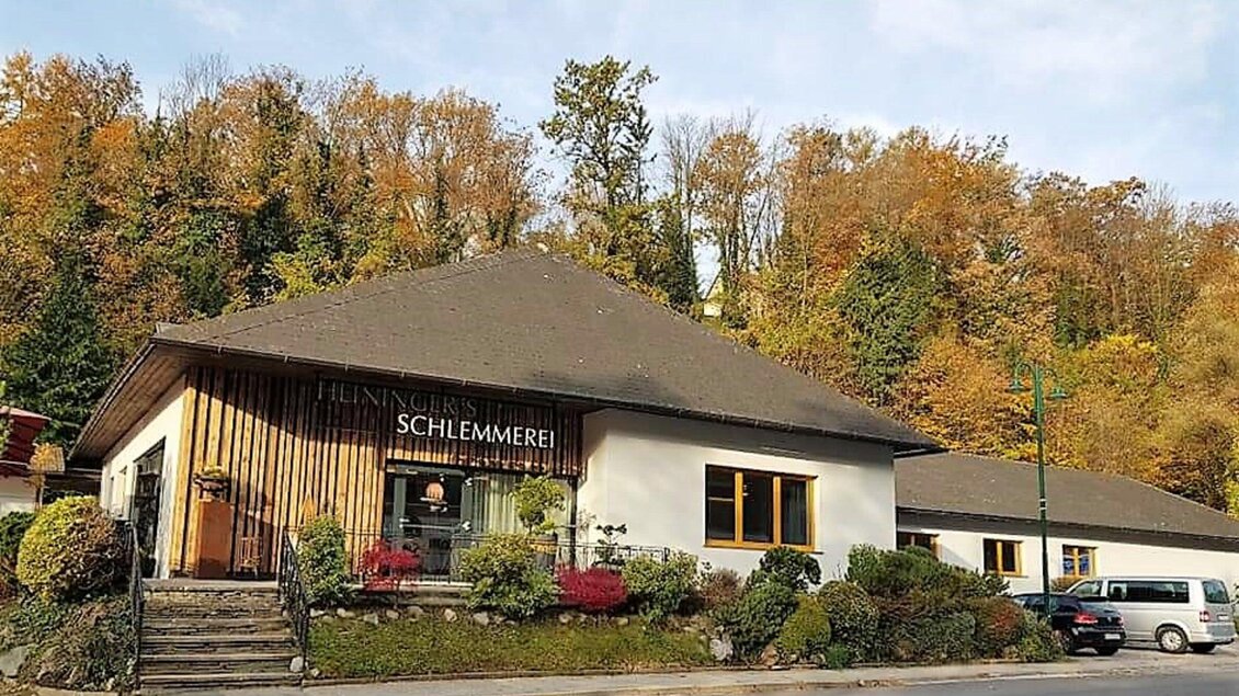 Ein gemütliches Restaurant mit dem Namen "Schlemmerei" in einer herbstlichen Umgebung. Bunte Blätter und grüne Pflanzen umgeben das Gebäude. | © Heiningers Schlemmerei
