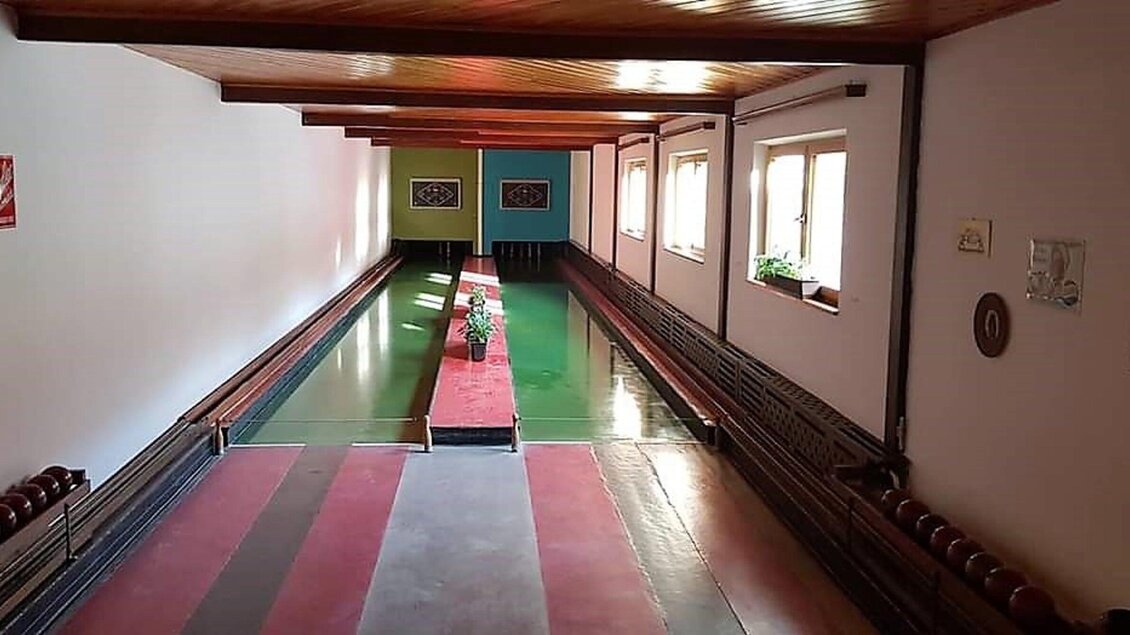 Ein Kegelbahn mit mehreren Bahnen und bunten Wänden. Der Raum ist gut beleuchtet und bietet Platz für mehrere Spieler. | © Heiningers Schlemmerei 