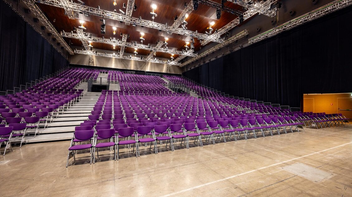 Ansteigende Tribüne mit lila Stühlen in der Helmut List Halle in Graz, leerer Veranstaltungsraum | © Graz Tourismus-Harry Schiffer
