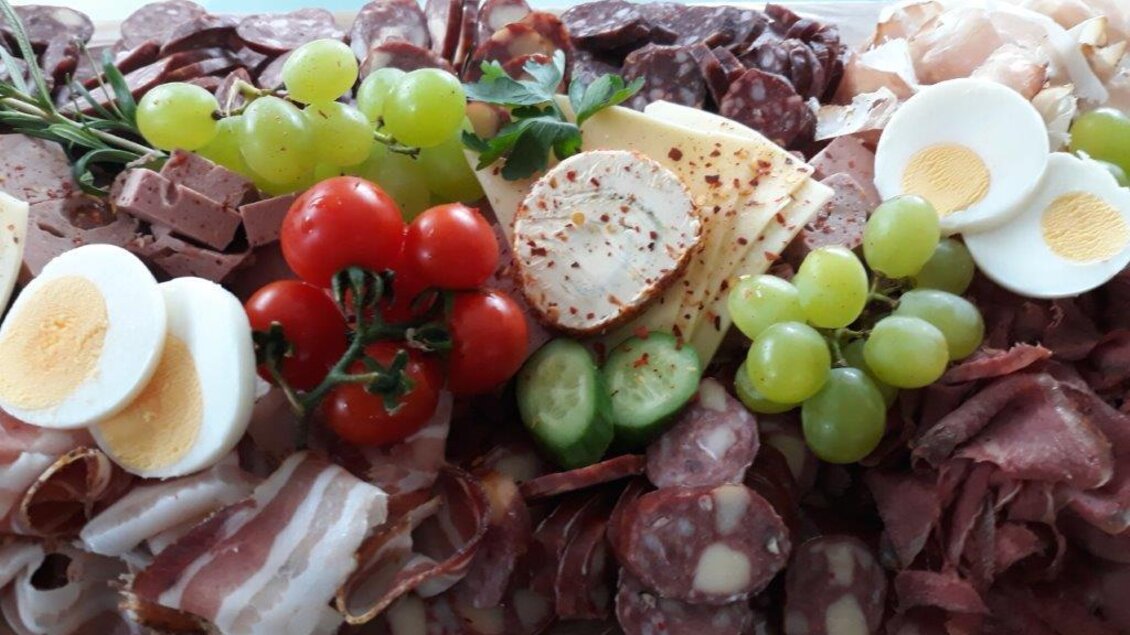Ein reichhaltiges Plattenangebot mit verschiedenen Wurstsorten, Käse, Eiern und frischem Obst. Die bunten Zutaten sind ansprechend angerichtet und sorgen für eine appetitliche Präsentation. | © Hirschgehege Hauser