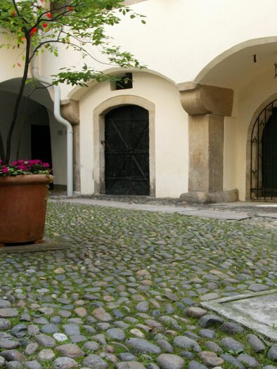 Pflasterhof mit Rundbögen, alten Türen und Topfpflanzen im Hof des Deutschen Ritterordens in Graz | © Graz Tourismus-Harry Schiffer