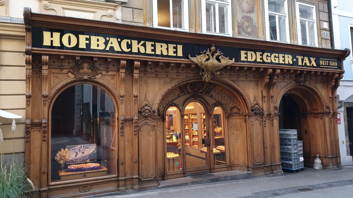 Eine traditionelle Bäckerei mit eindrucksreicher Holzfassade und großen Fenstern. Das Schild zeigt den Namen "Hofbäckerei Ed Edger-Tax" und das Gründungsjahr. | © Gudrun Krinzinger - Reisebloggerin