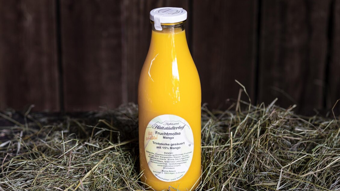 Eine Flasche frisch gepresster Saft steht auf einem Bett aus Heu. Der Saft hat eine leuchtend orange Farbe. | © Martin Huber