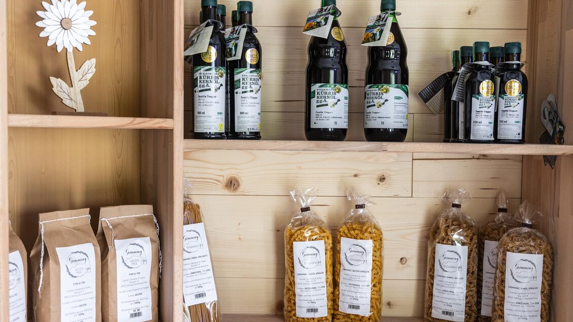 Regale mit verschiedenen Produkten, darunter Olivenöl und Pasta. Die Regale sind aus hellem Holz und die Verpackungen sind klar beschriftet. | © Martin Huber