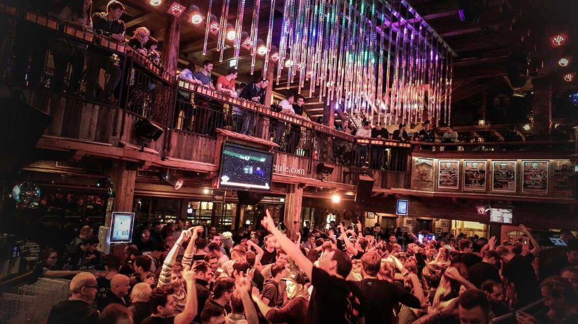 Ein lebhaftes Nachtleben in einer Bar mit vielen Menschen, die tanzen und feiern. Bunte Lichter hängen von der Decke und schaffen eine festliche Atmosphäre. | © Pressefoto Scharinger