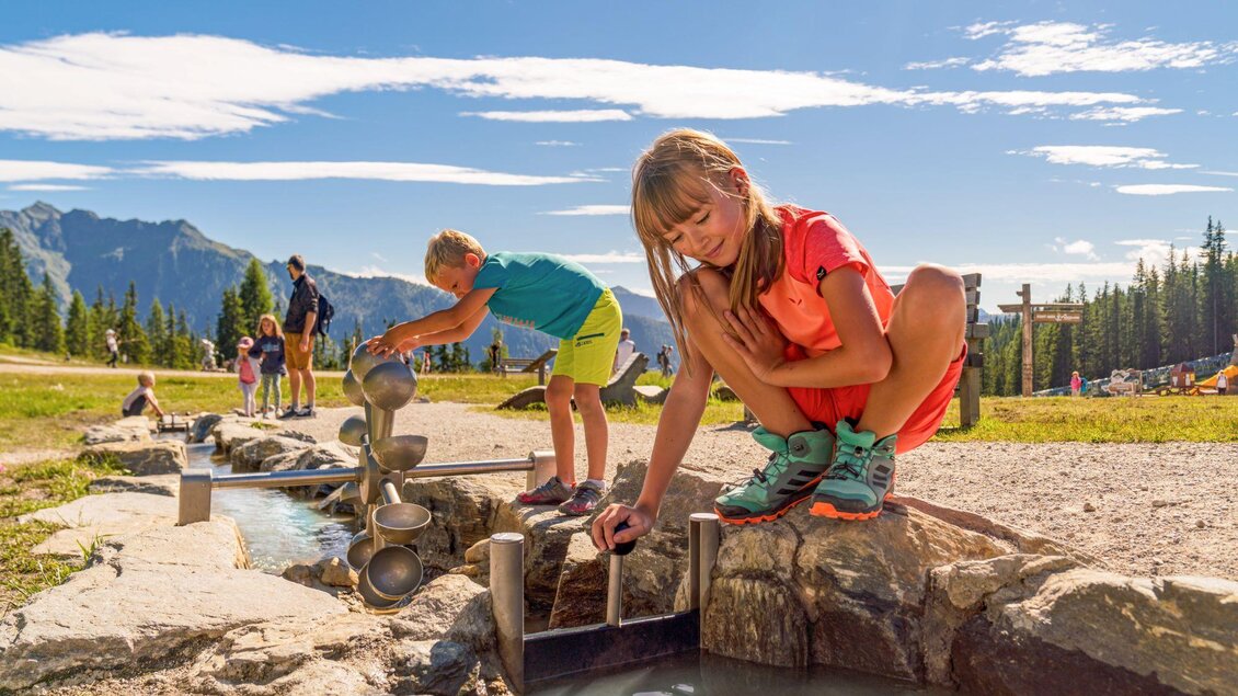 Ein Spielplatz in der Natur mit Wasserläufen. Kinder spielen und experimentieren glücklich im Freien. | © Christine Höflehner